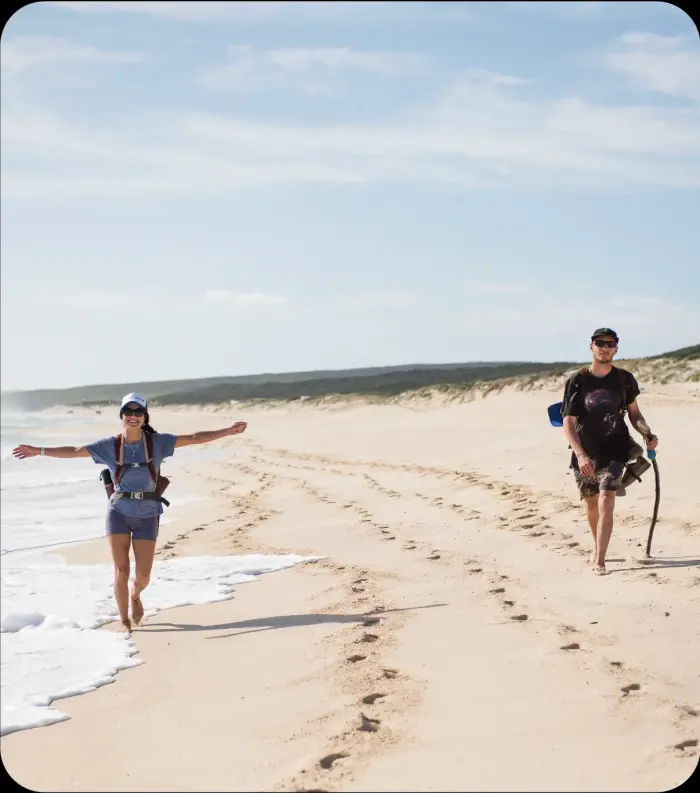 Hikers walking along the beach on a Cape2Camp self-guided adventure