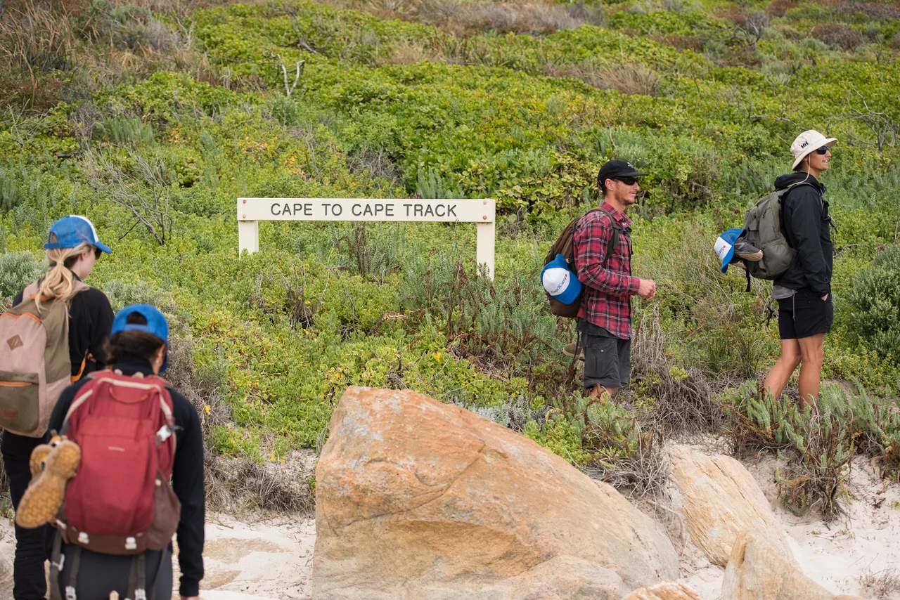 Hikers at a Cape to Cape Track sign on a Cape2Camp day hike